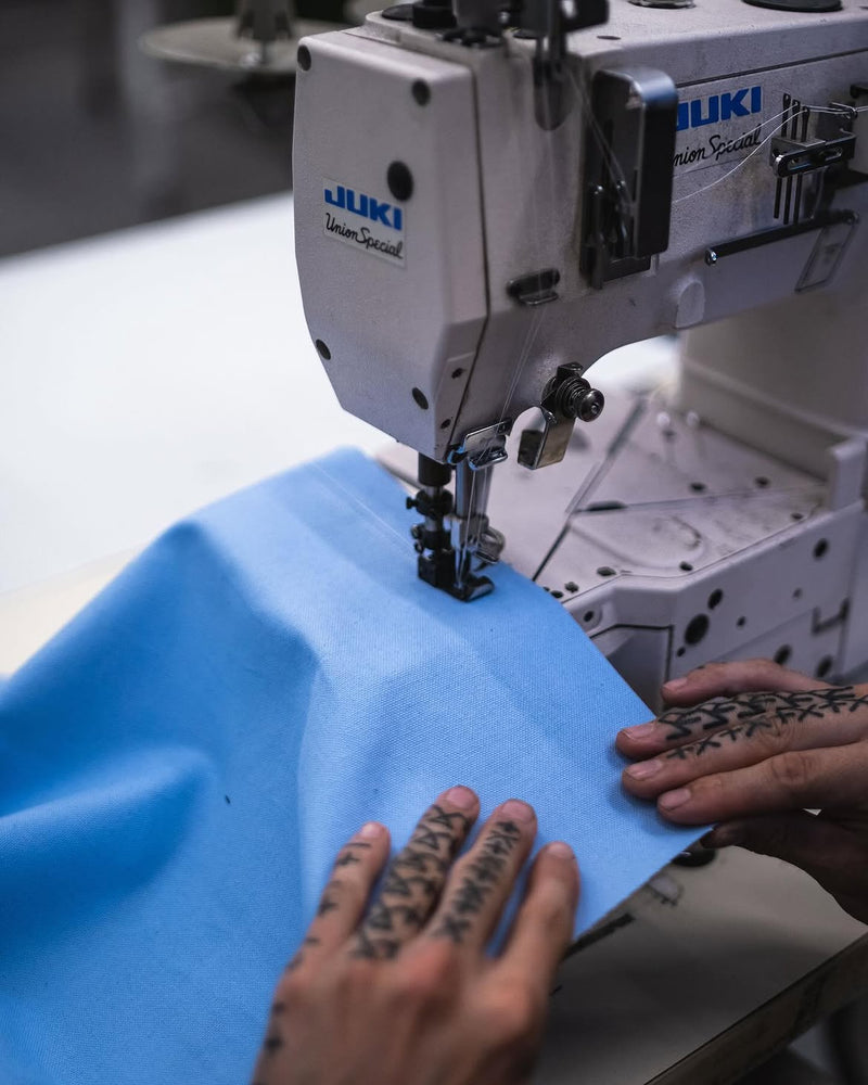 Garment maker cutting and sewing fabric during the custom apparel production process at In-House.