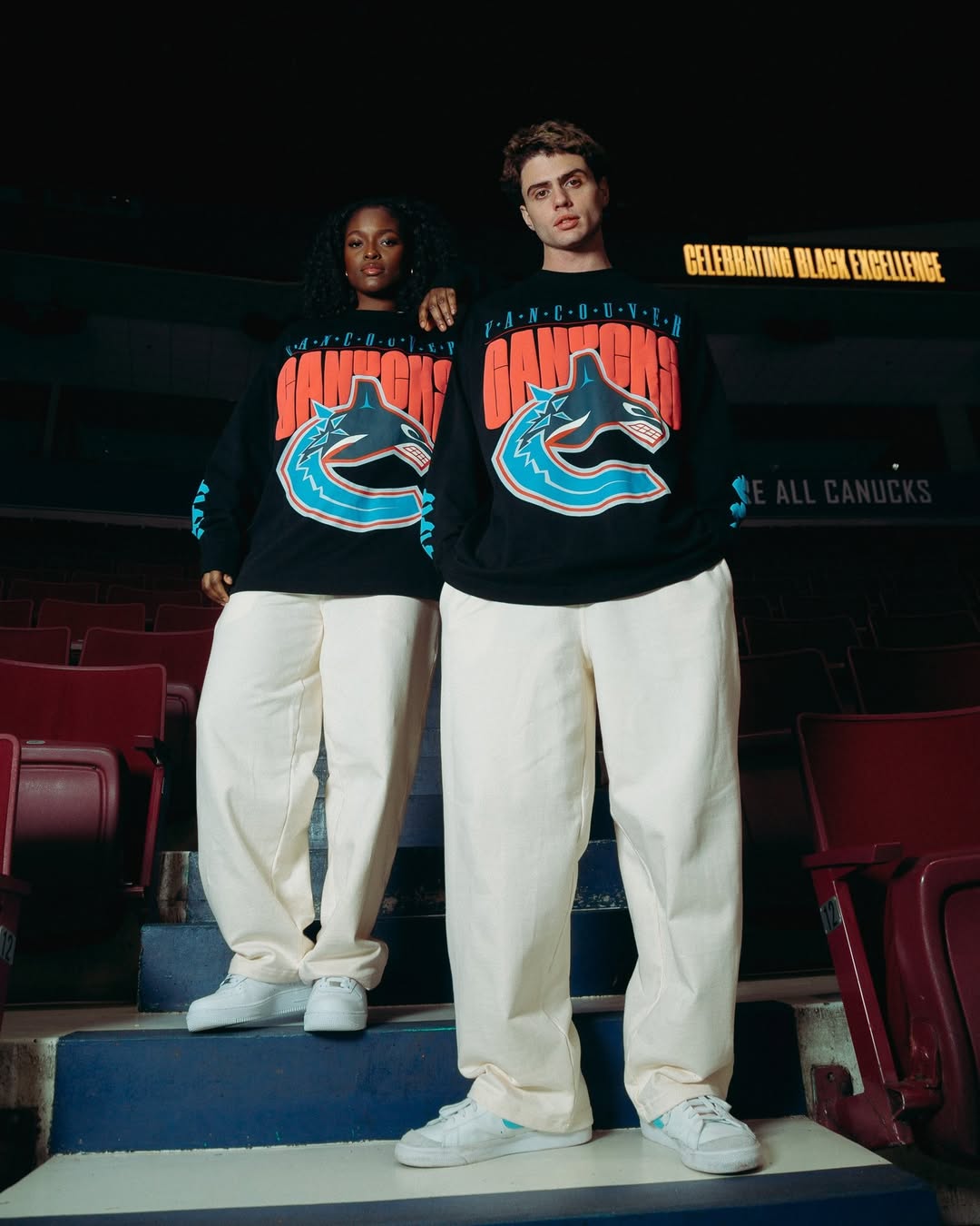 A man and woman standing together wearing an In-House designed custom T-shirt.